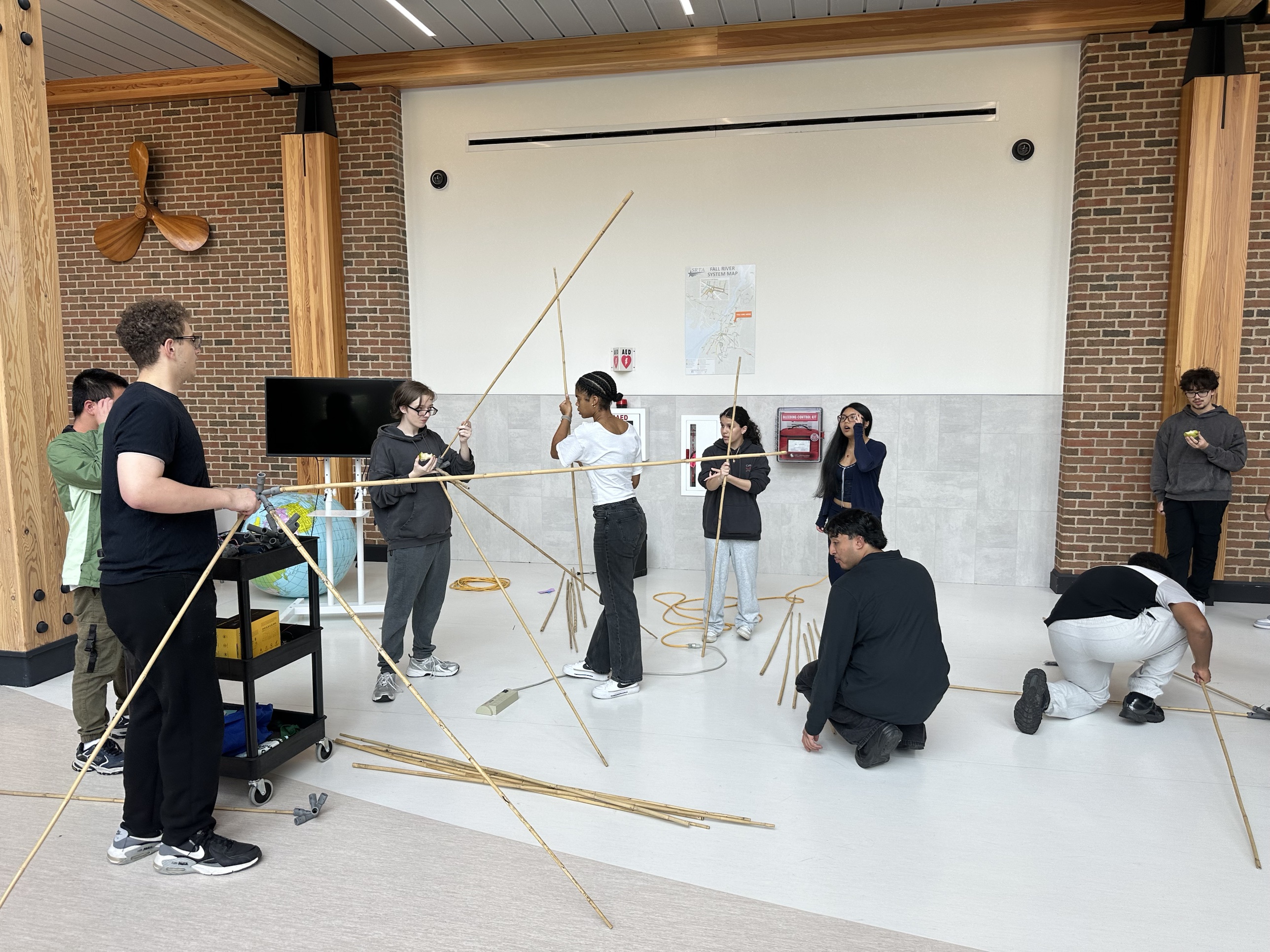 Students pushing bamboo poles into 3D-printed hubs to assemble the icosahedron