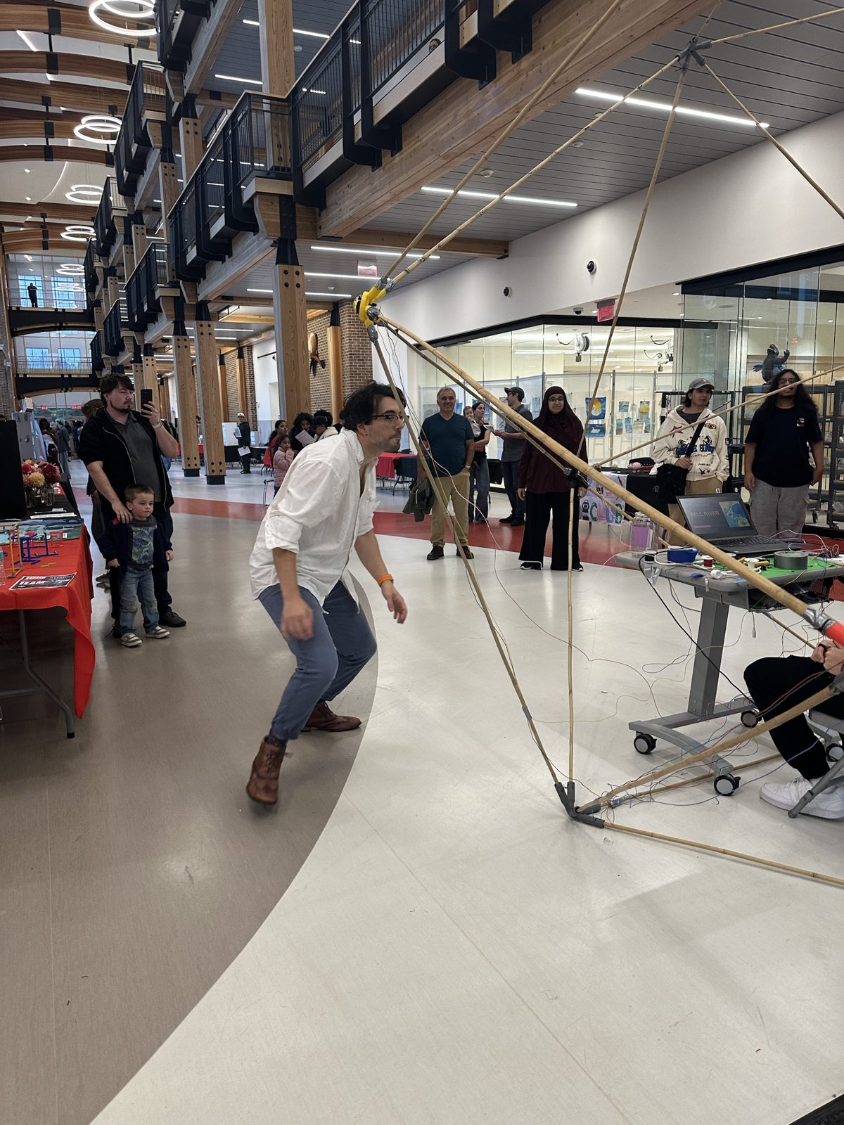 Visitors watching a player lunge for a button on the GeoGlobe frame at the open house